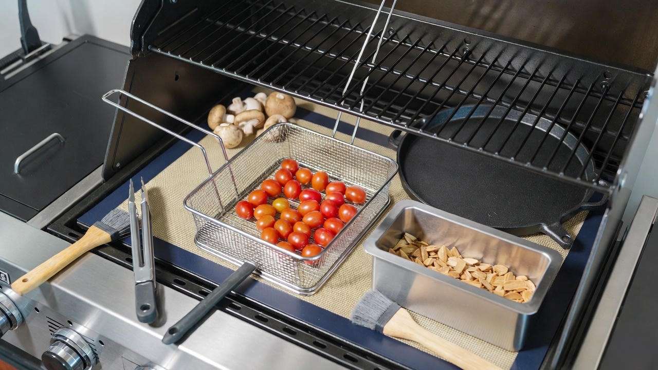 Essential vegan grilling accessories arranged on Coyote grill side shelf including basket, plancha and smoker box